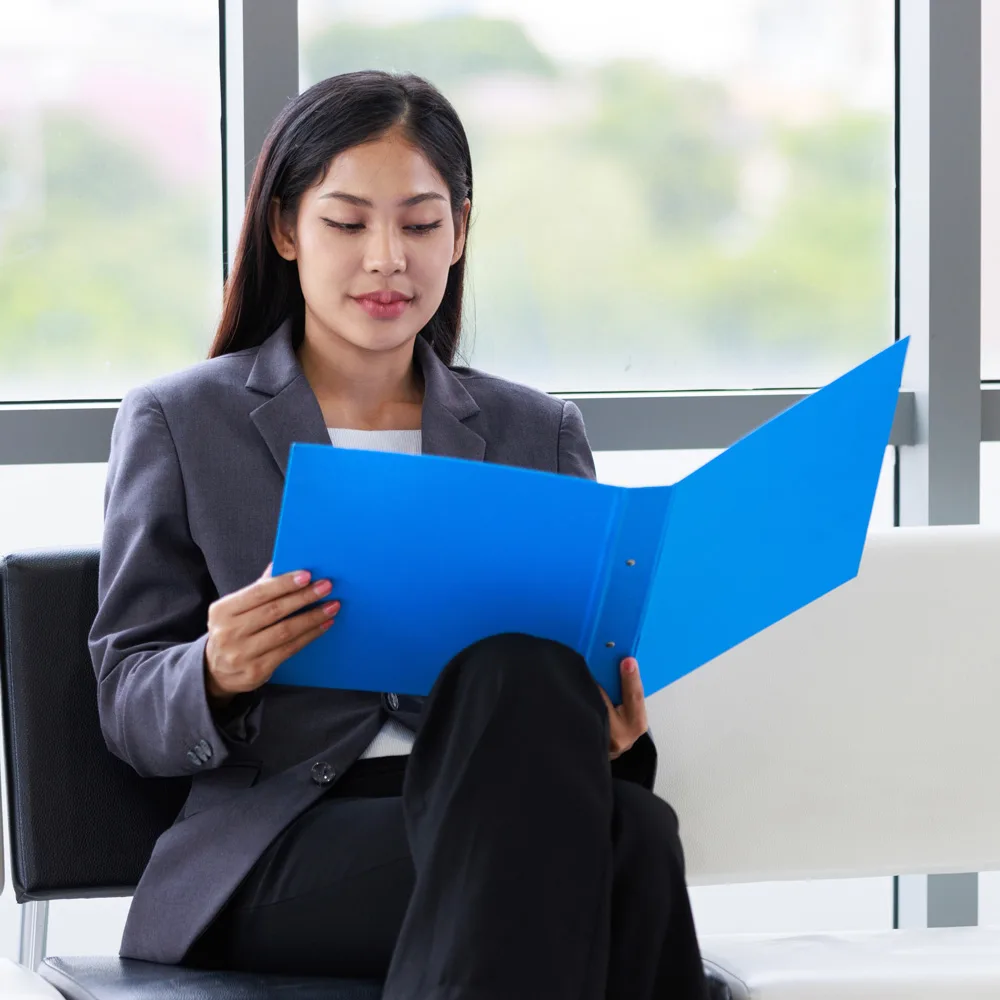 Businesswoman reading a blue folder while seated